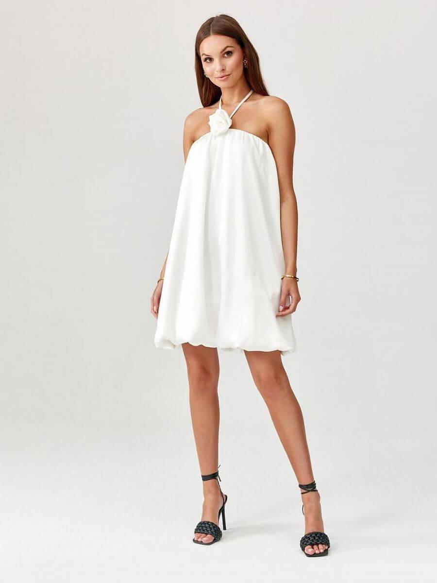 Model showcasing a bombshell cocktail dress in white, featuring a unique cut and elegant design.