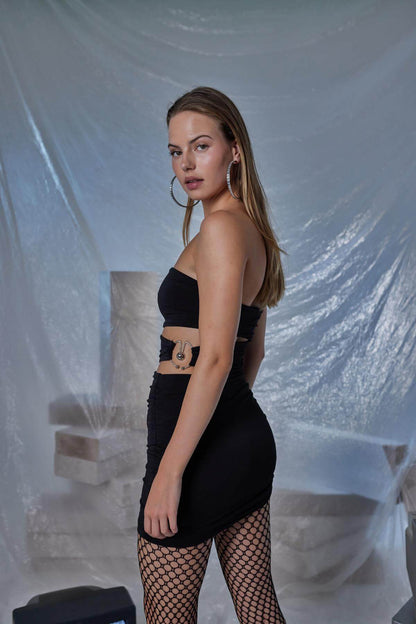 Model wearing a stylish black pleated mini bodycon dress, showcasing elegance with a figure-hugging silhouette.