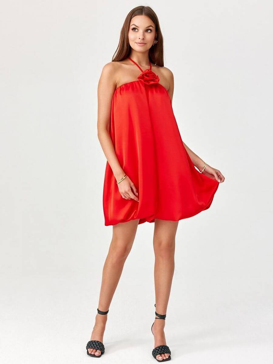 Model showcasing a bombshell cocktail dress with a floral detail in vibrant red fabric.