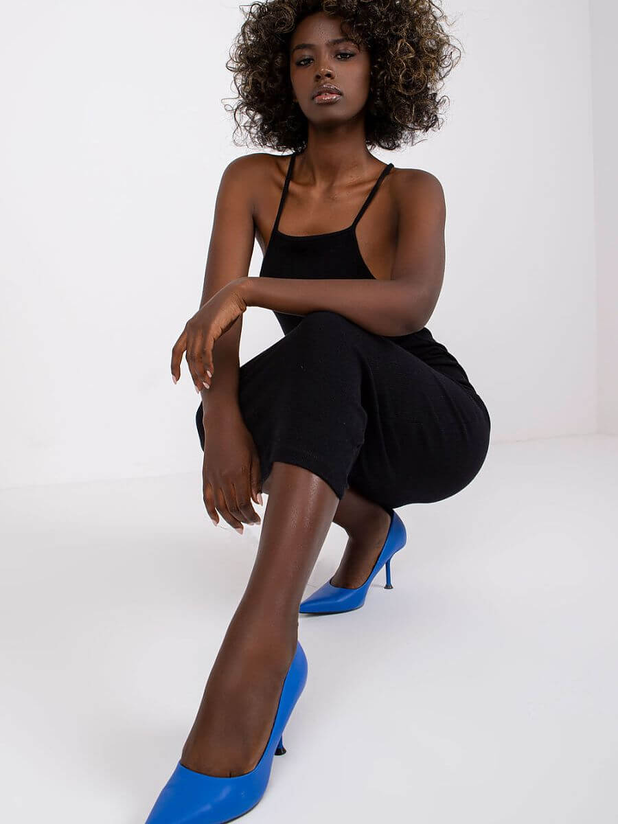 Model wearing a summer pencil dress with blue heels, showcasing a stylish summer look in a bright setting.