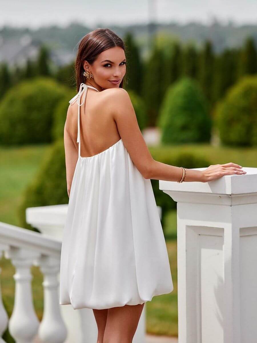 Back view of a model in a bombshell cocktail dress, showcasing its elegant design and flattering silhouette.